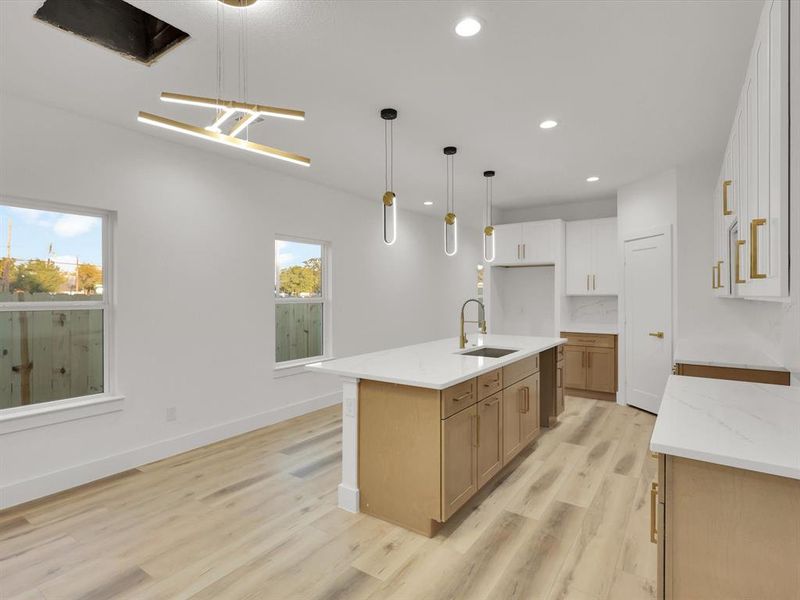 Kitchen with sink, white cabinets, plenty of natural light, and a center island with sink