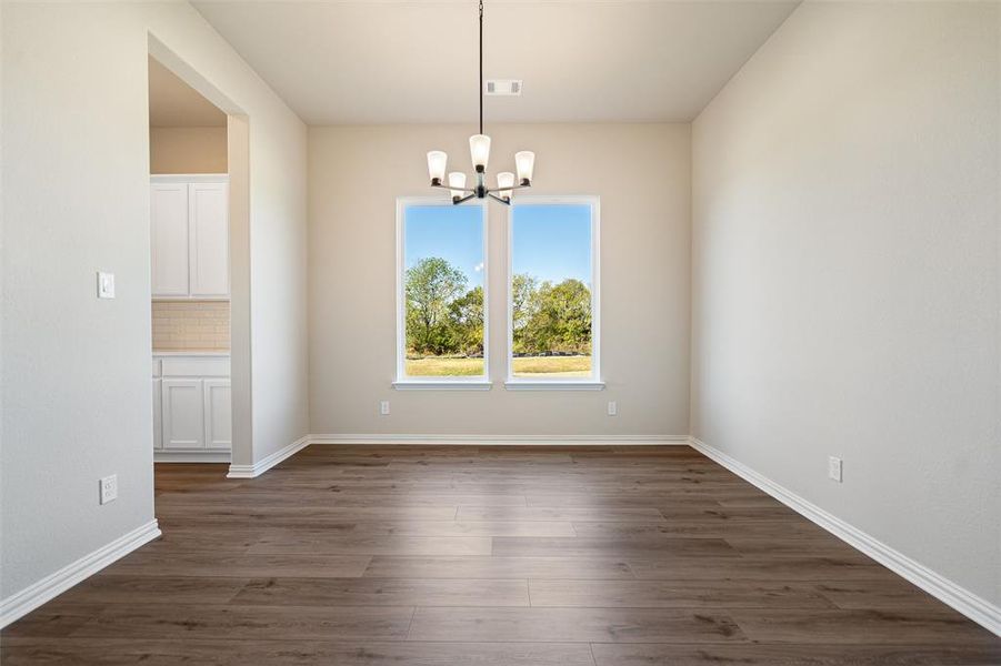 Unfurnished dining area with dark wood-style flooring and a chandelier