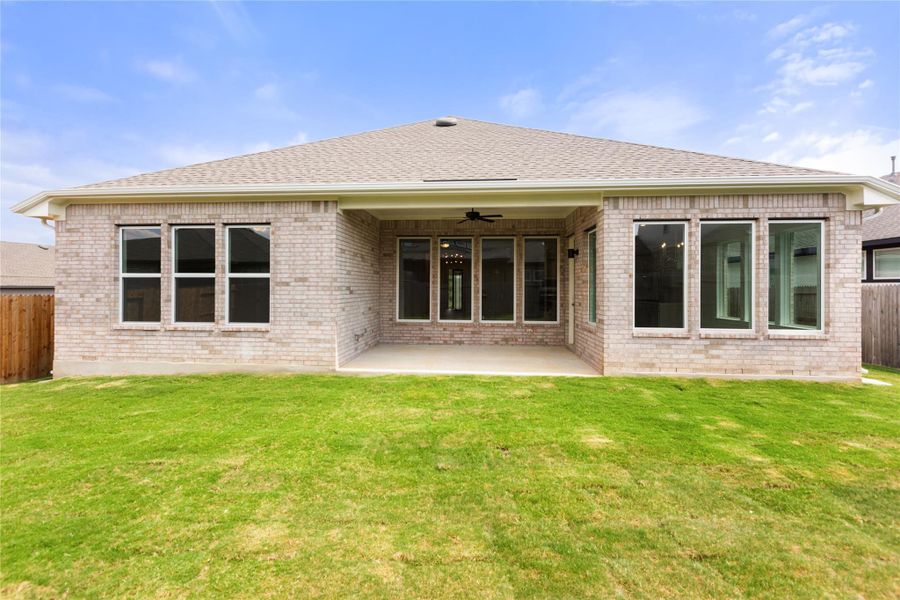 Rear view of property featuring ceiling fan, brick siding, a patio, and a shingled roof