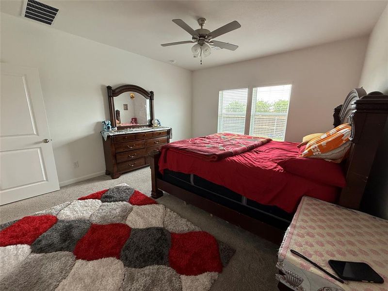 Bedroom featuring two windows with blinds, a ceiling fan with light fixture, carpet flooring, and white walls