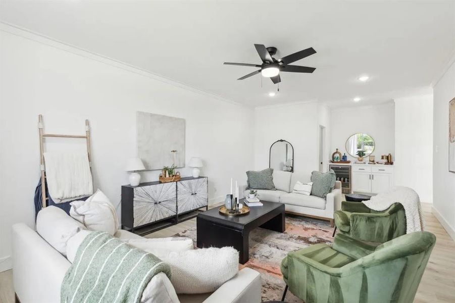 Living room featuring beverage cooler, light wood finished floors, ornamental molding, ceiling fan, and recessed lighting