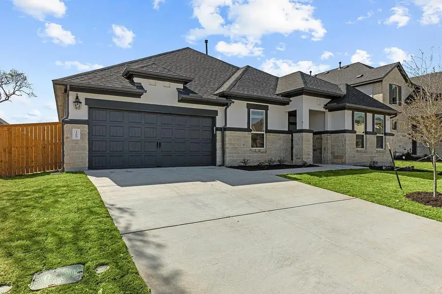 The property features a concrete driveway, a two-car garage, and a well-maintained lawn