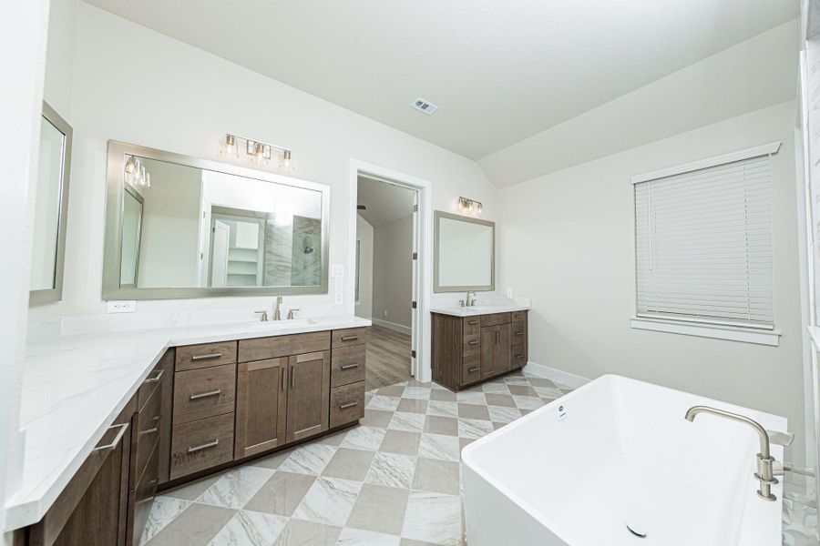 Modern primary bath features dual vanities with sleek white cabinetry, a quartz countertop, framed vanity mirrors, and brushed nickel fixtures for a truly contemporary feel.