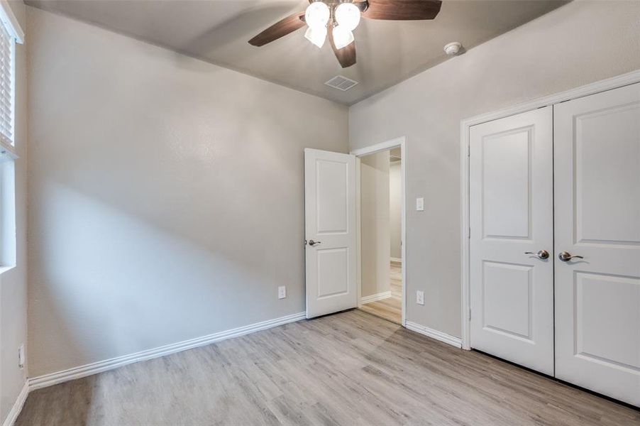 Unfurnished bedroom with light wood finished floors, ceiling fan, and a closet