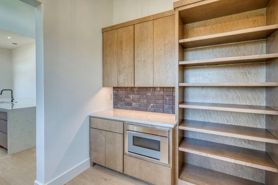 Custom wood cabinetry and built-in shelving flank a convenient prep counter with integrated microwave.