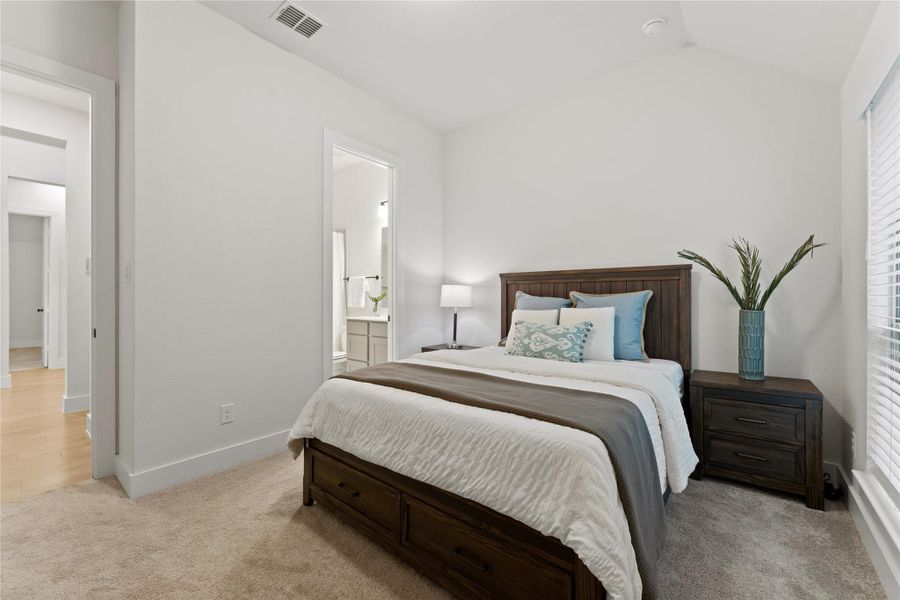Carpeted bedroom featuring a vaulted ceiling and a window with blinds