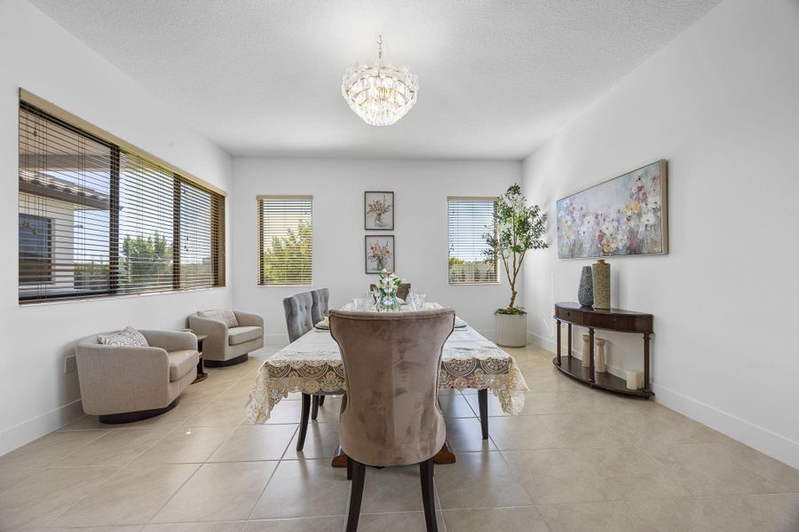Dining space with healthy amount of natural light, a chandelier, light tile patterned floors, and a textured ceiling