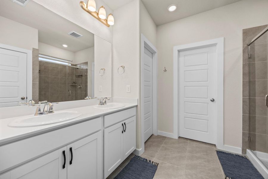 Step into the primary en-suite, designed for convenience and style. The bathroom boasts a double vanity with bright lighting, a separate toilet closet, and a beautifully tiled walk-in shower.