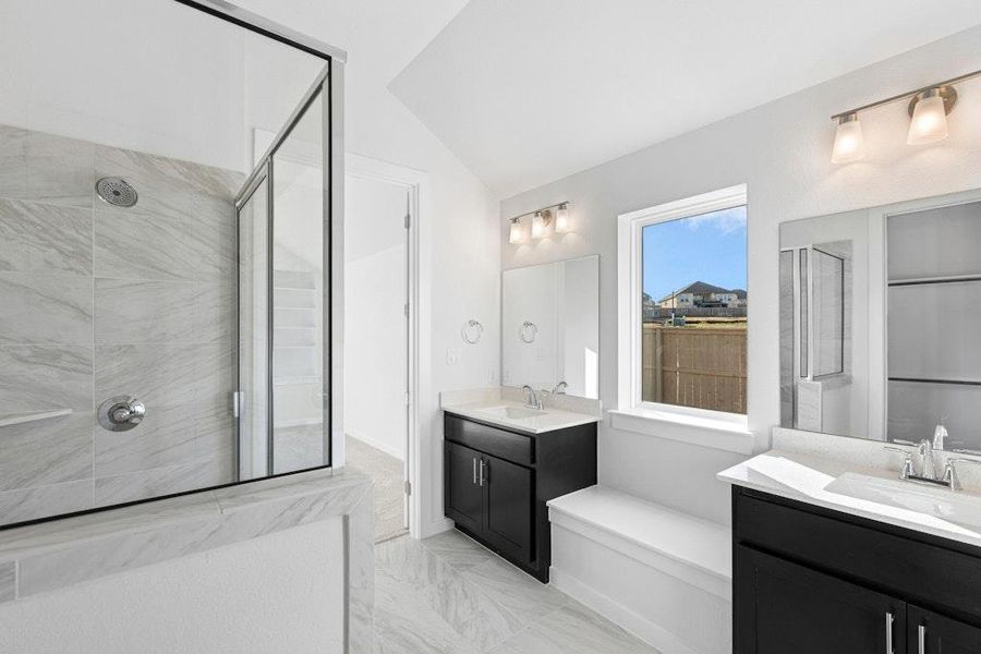 Full bath with a stall shower, light marble finish floors, two vanities, and lofted ceiling