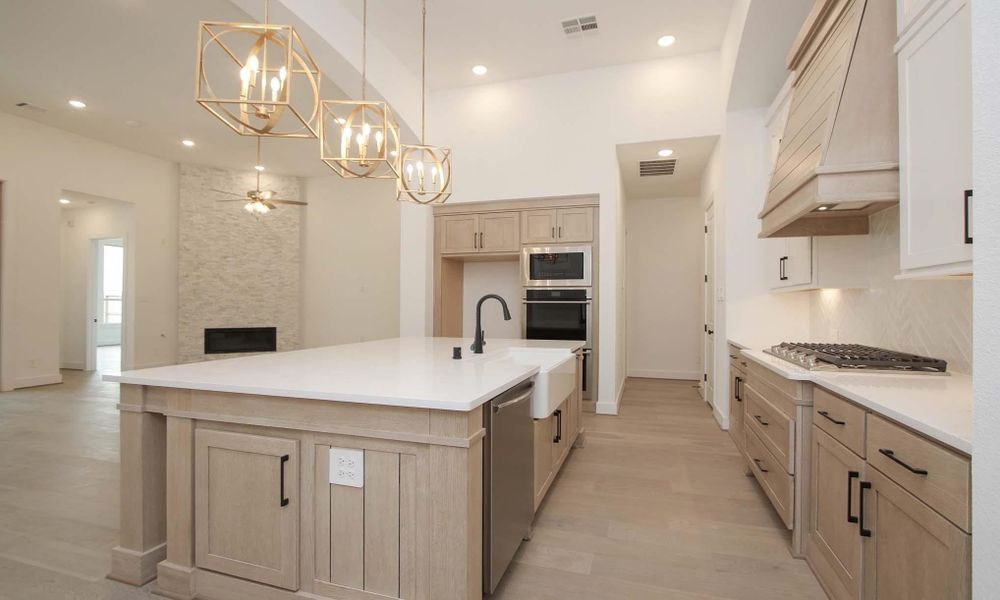 Kitchen with a chandelier, ceiling fan, premium range hood, appliances with stainless steel finishes, and a large island