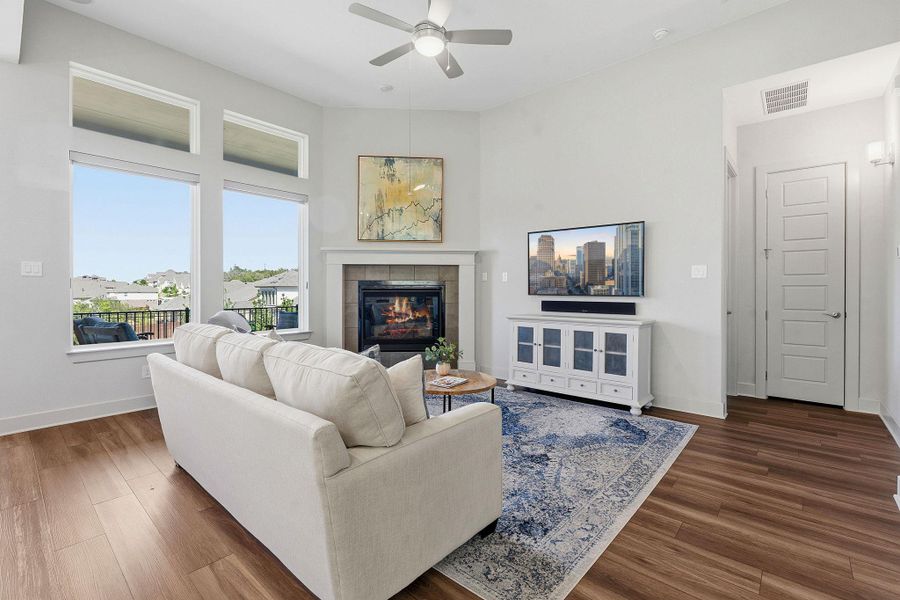 Living room featuring ceiling fan, dark wood-style floors, and a tiled fireplace Living room featuring ceiling fan, dark wood-style floors, and a tiled fireplace