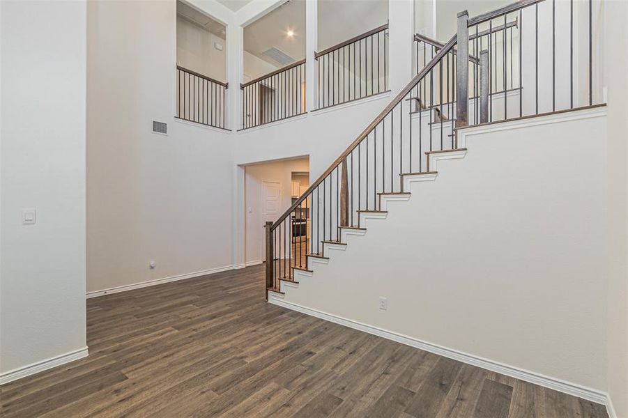 Stairs with a towering ceiling and hardwood / wood-style floors