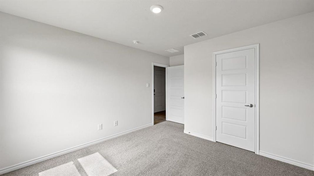 Neutral-toned room featuring a five-panel interior door, plush gray carpeting, and white baseboards Neutral-toned room featuring a five-panel interior door, plush gray carpeting, and white baseboards