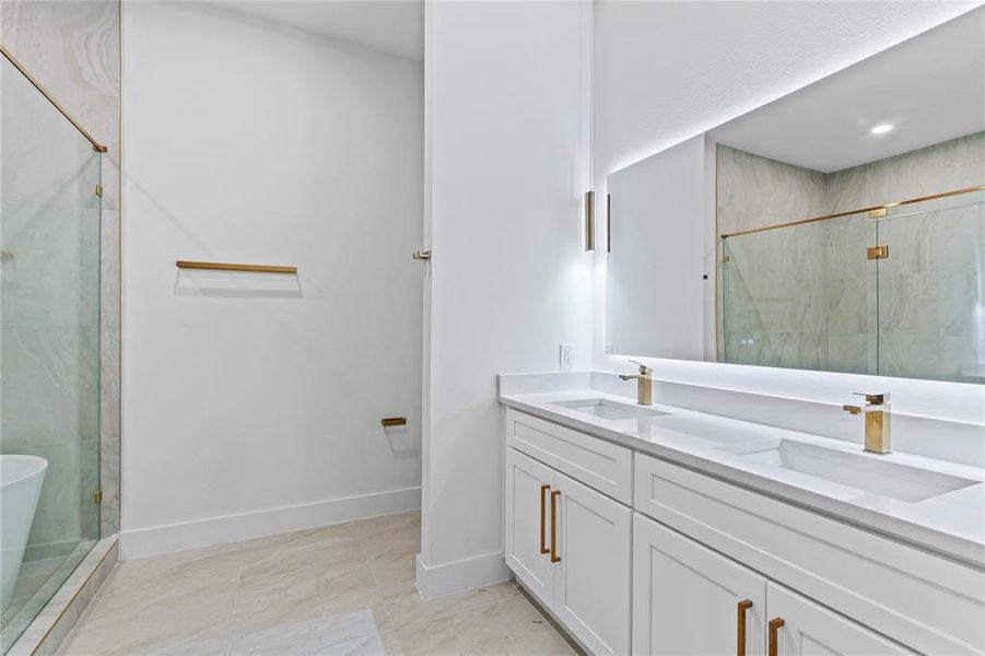 Full bathroom with double vanity, a shower stall, baseboards, and a freestanding bath Full bathroom with double vanity, a shower stall, baseboards, and a freestanding bath