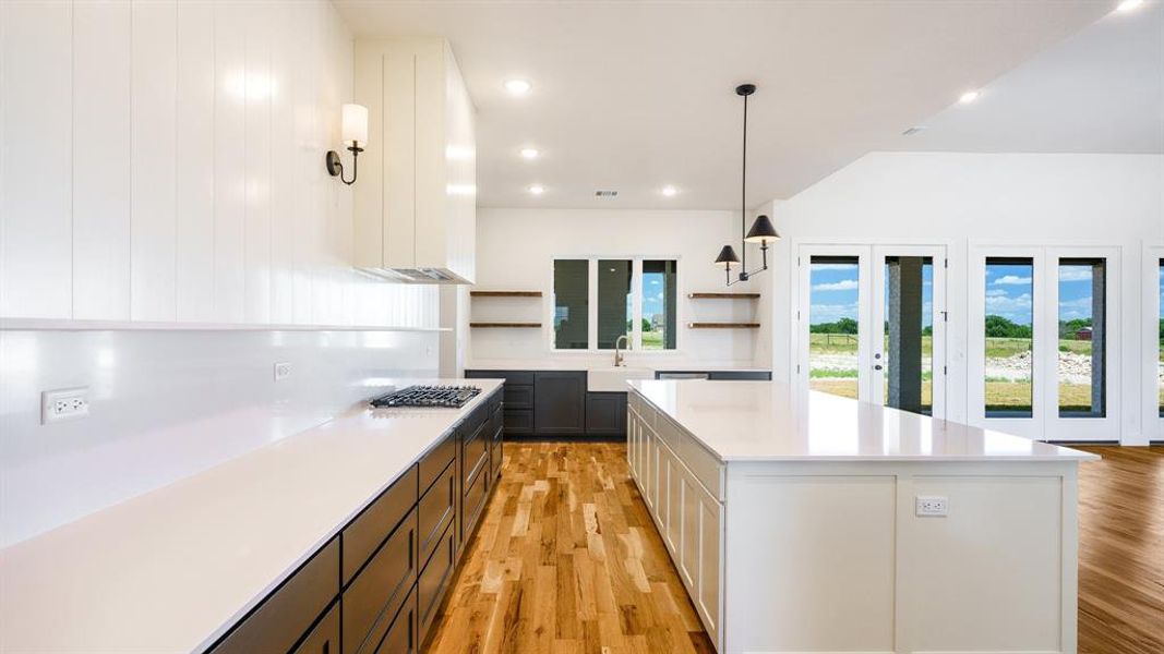 Kitchen with a kitchen island, decorative light fixtures, light wood-type flooring, and white cabinetry