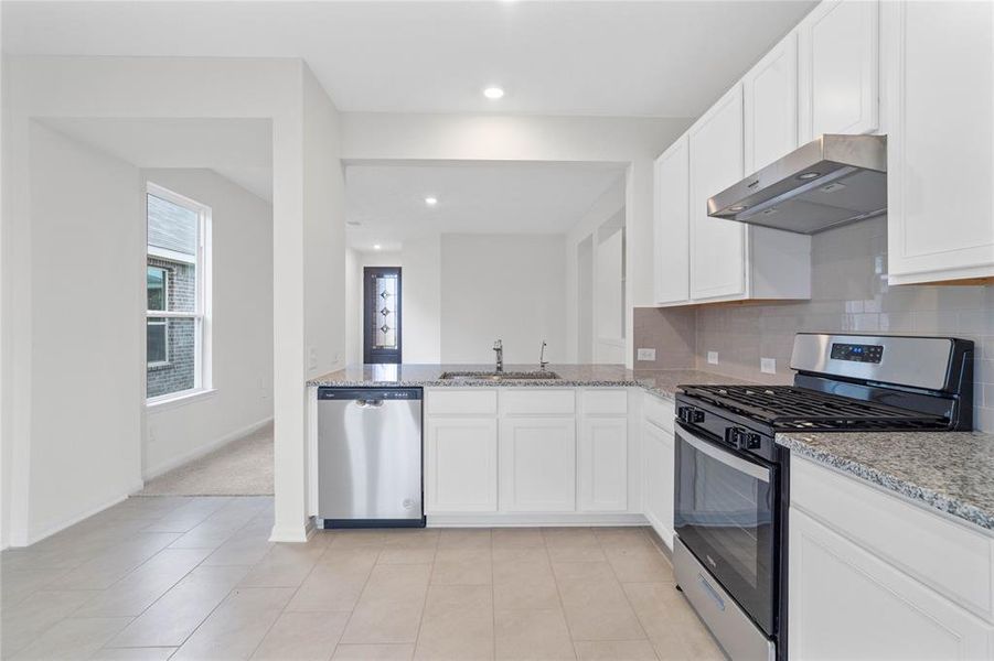 This spacious kitchen features high ceilings, stained wood cabinets, granite countertops, SS appliances, modern tile backsplash, recessed lighting, and a walk-in pantry all overlooking your huge family room.