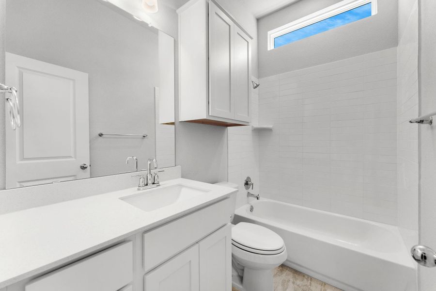 A well-appointed bath features a sleek vanity, convenient overhead cabinetry, and a bright window. A well-appointed bath features a sleek vanity, convenient overhead cabinetry, and a bright window.