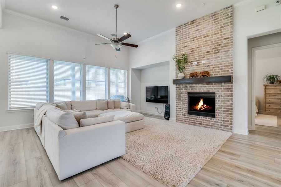 Living area featuring wood finished floors, visible vents, baseboards, a fireplace, and ceiling fan Living area featuring wood finished floors, visible vents, baseboards, a fireplace, and ceiling fan