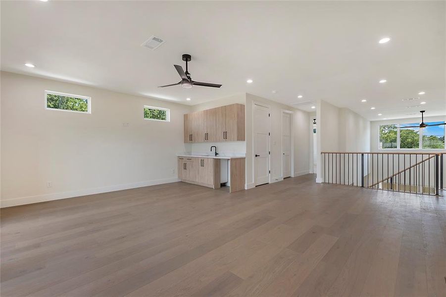 Unfurnished living room with sink, ceiling fan, and hardwood / wood-style floors