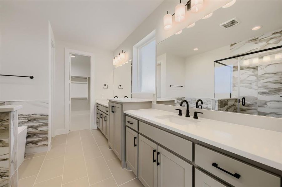 Bathroom featuring dual vanities with white countertops, matte black fixtures, and light grey cabinetry
