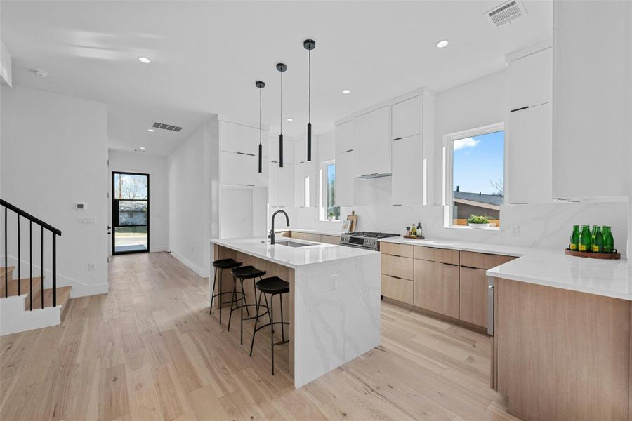 Kitchen with modern cabinets, a center island with sink, light stone counters, a kitchen bar, and recessed lighting Kitchen with modern cabinets, a center island with sink, light stone counters, a kitchen bar, and recessed lighting