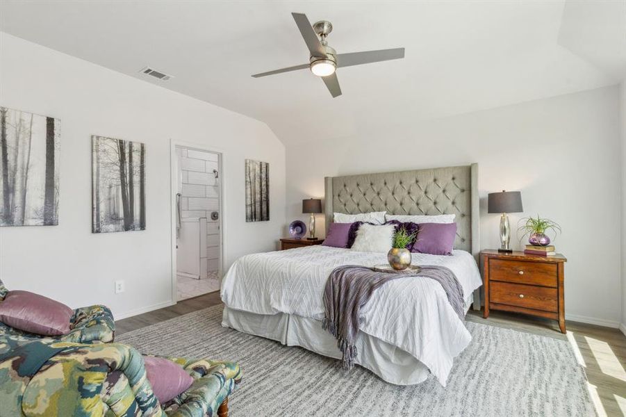 Bedroom featuring lofted ceiling, ensuite bathroom, light wood-type flooring, and ceiling fan