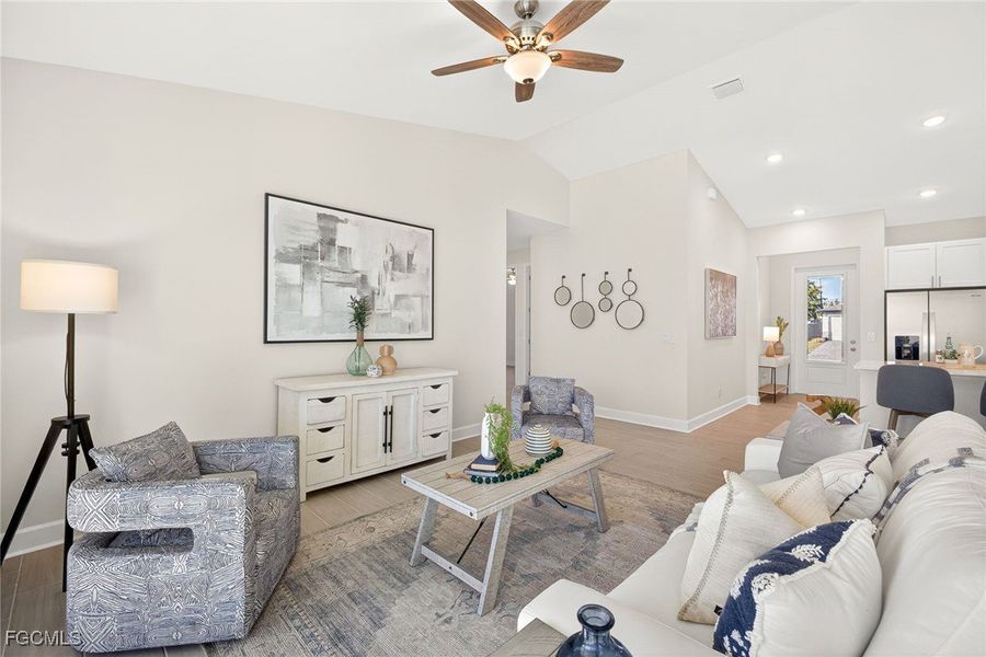 Living room featuring lofted ceiling, wood finished floors, a ceiling fan, and recessed lighting