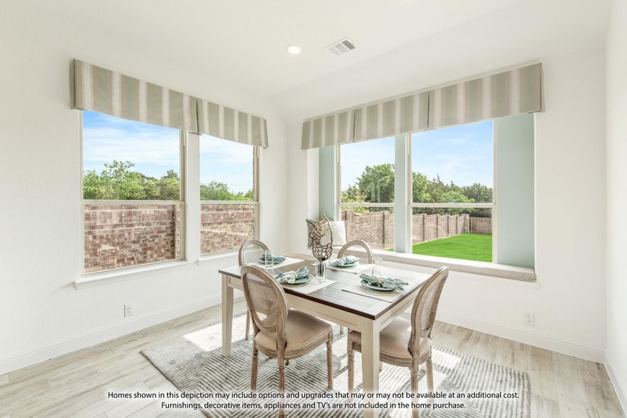Bright dining area with four-chair table, large windows, and backyard views on light wood floors