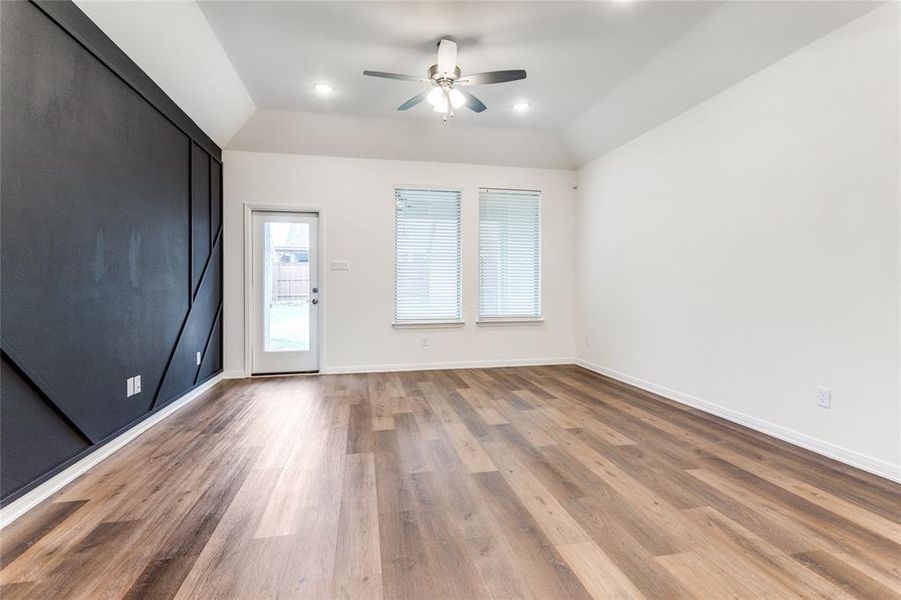 Living room with ceiling fan, vaulted ceiling, and wood-style floors - view to the back yard