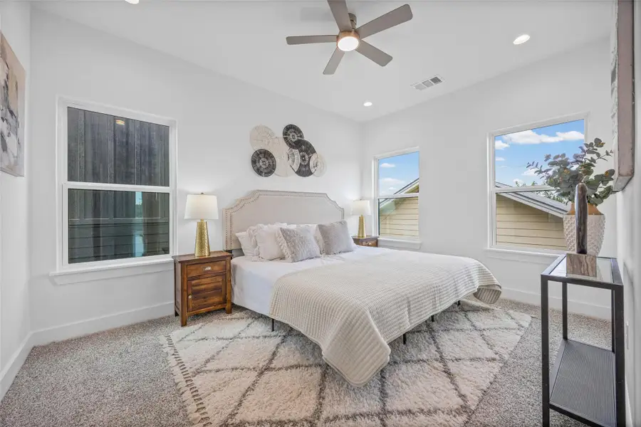 Natural light floods this inviting bedroom, highlighting the plush carpeting and contemporary ceiling fan. Natural light floods this inviting bedroom, highlighting the plush carpeting and contemporary ceiling fan.