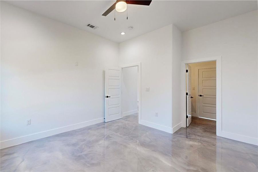 Unfurnished bedroom featuring a high ceiling, concrete flooring, and ceiling fan