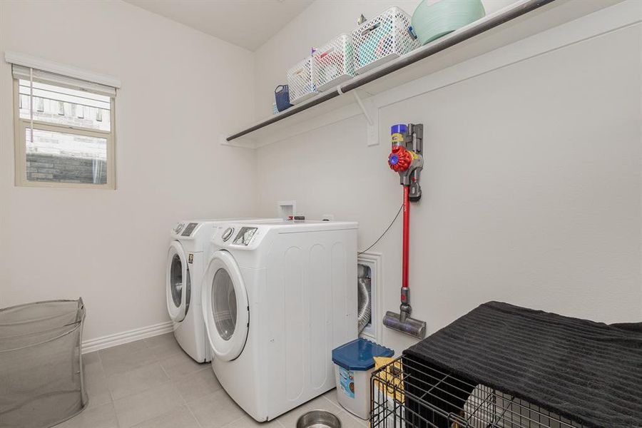 Clothes washing area with light tile patterned floors and washer and dryer