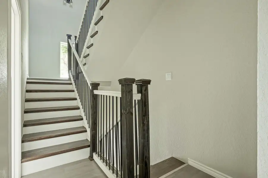 Stairway featuring wood finished floors and a textured wall