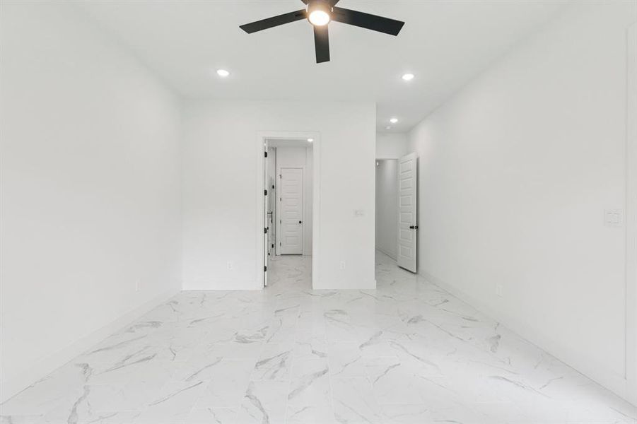 Unfurnished bedroom featuring ceiling fan, light marble finish floors, and recessed lighting