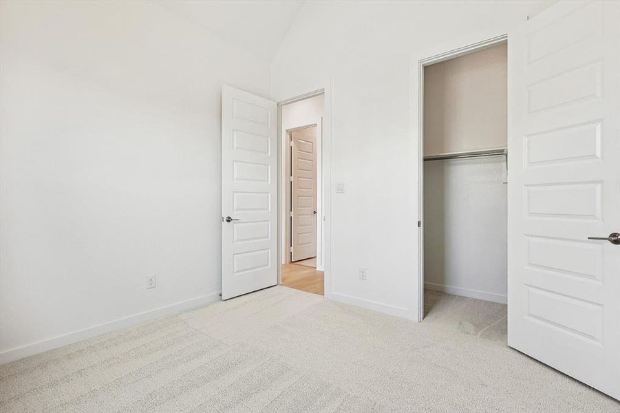 Unfurnished bedroom with lofted ceiling, light carpet, and a closet