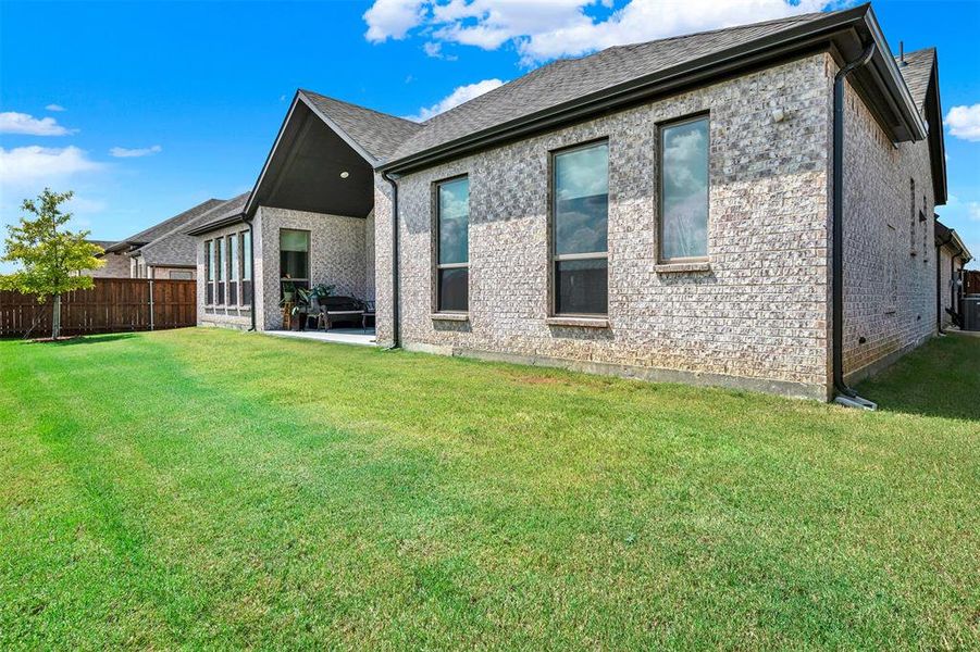 Back of house featuring a patio, brick siding, and roof with shingles