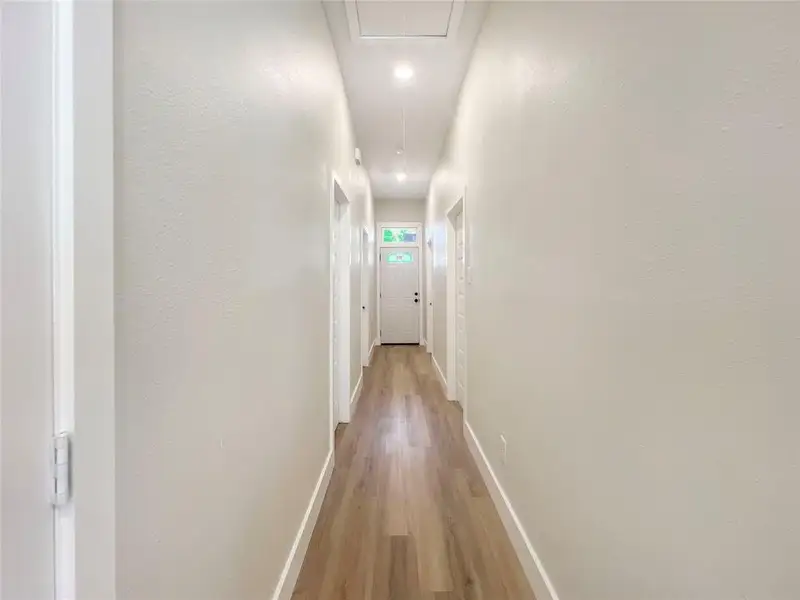 Corridor with attic access, light wood-style floors, and baseboards