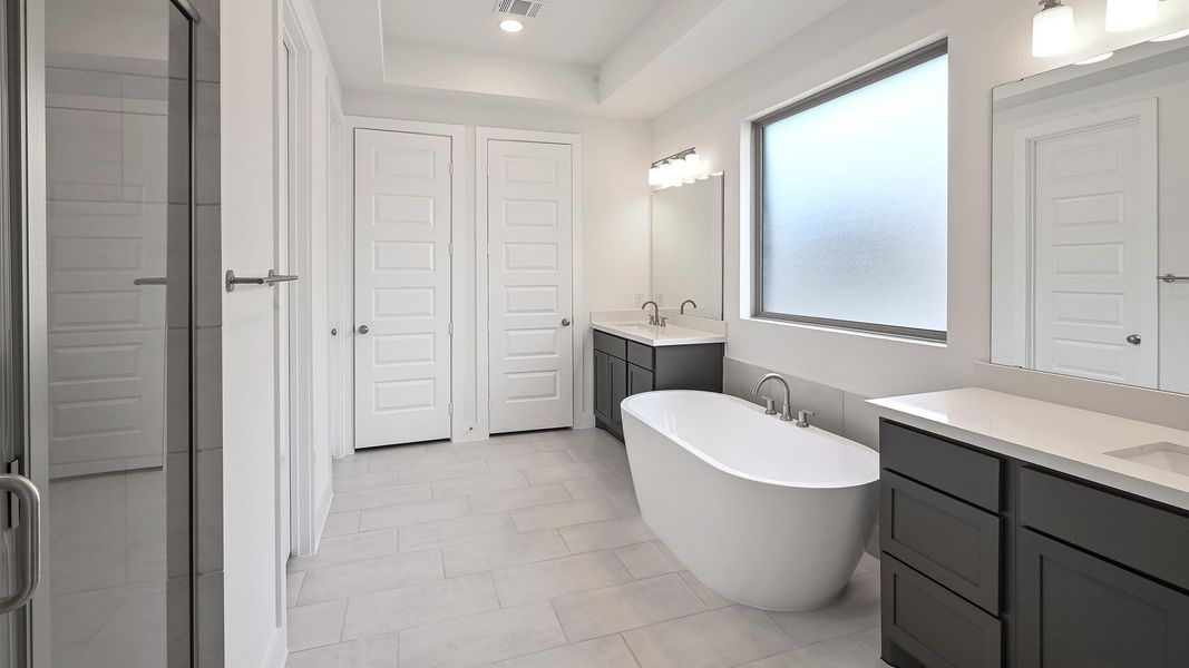Full bathroom featuring two vanities, a freestanding tub, light tile patterned floors, a shower stall, and recessed lighting Full bathroom featuring two vanities, a freestanding tub, light tile patterned floors, a shower stall, and recessed lighting