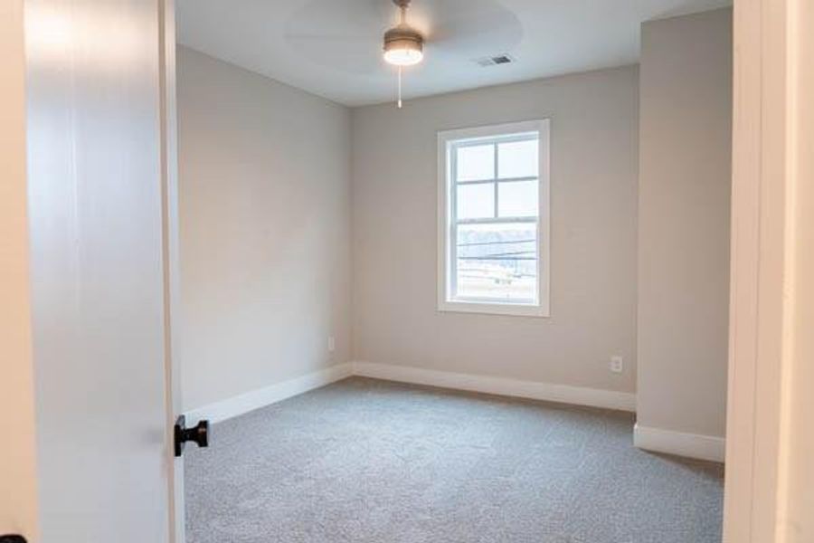 Empty room featuring ceiling fan, a healthy amount of sunlight, and light carpet Empty room featuring ceiling fan, a healthy amount of sunlight, and light carpet