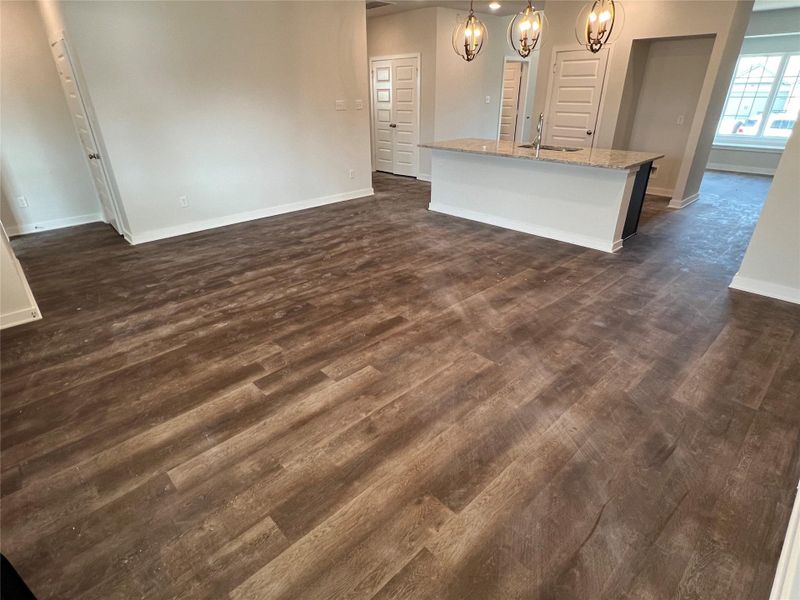 Unfurnished living room featuring dark wood-type flooring and a chandelier Unfurnished living room featuring dark wood-type flooring and a chandelier