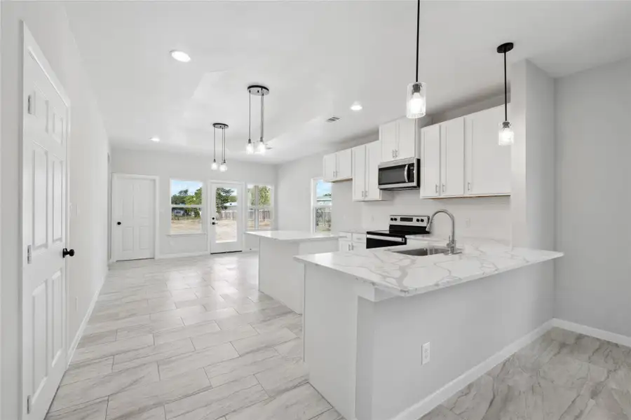 Kitchen featuring stainless steel microwave, a sink, electric stove, baseboards, and recessed lighting Kitchen featuring stainless steel microwave, a sink, electric stove, baseboards, and recessed lighting