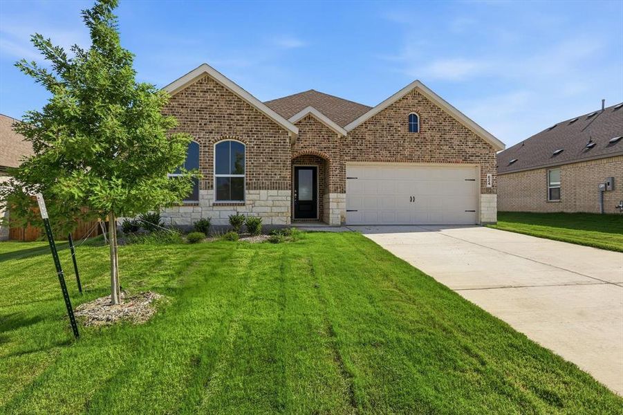 Brick facade featuring stone accents, arched windows, an attached two-car garage, and a concrete driveway Brick facade featuring stone accents, arched windows, an attached two-car garage, and a concrete driveway