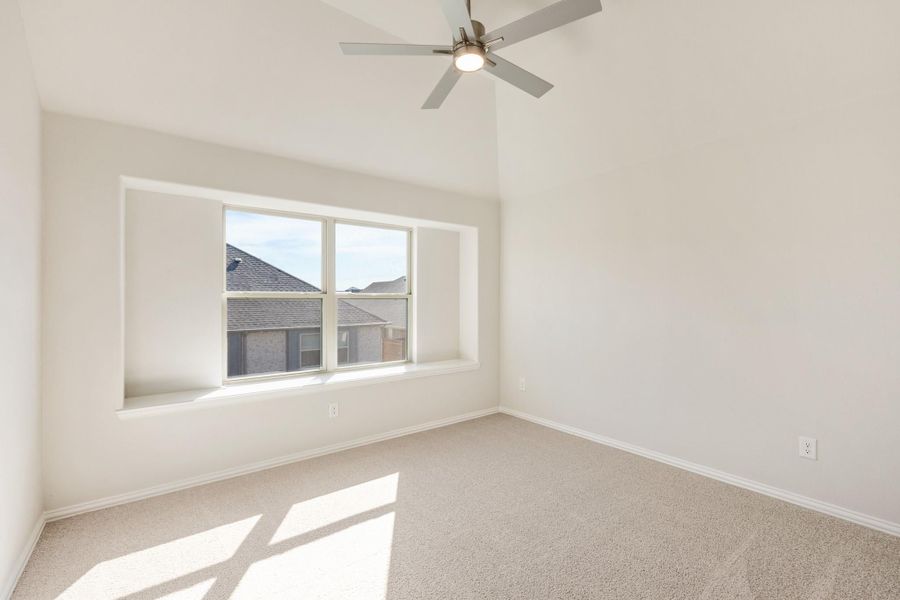Empty bedroom with vaulted ceiling, ceiling fan, carpet flooring, and large window Empty bedroom with vaulted ceiling, ceiling fan, carpet flooring, and large window