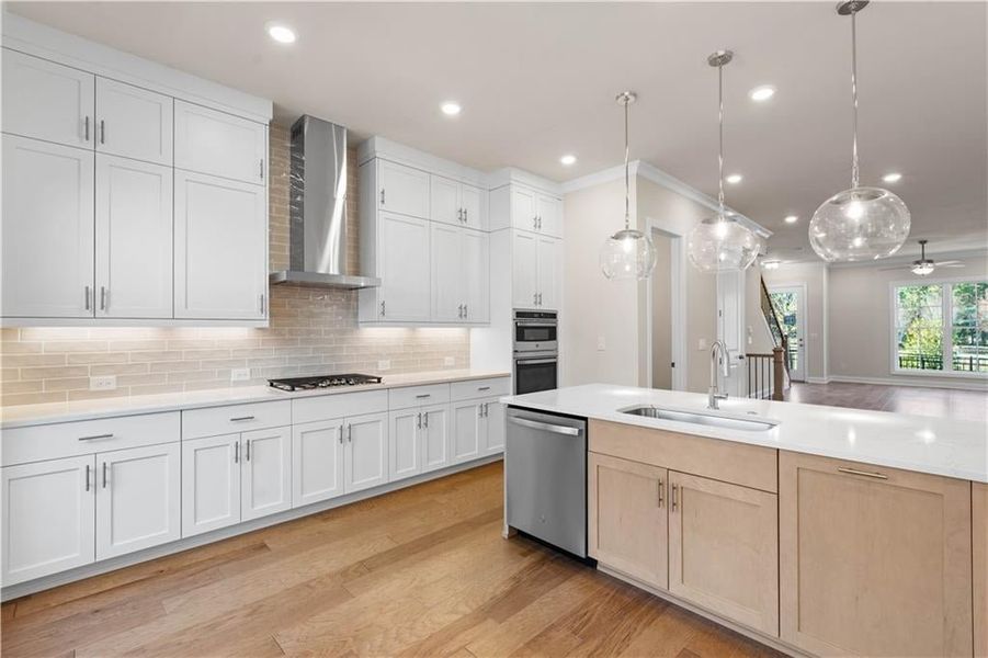 Kitchen with light wood-type flooring, tasteful backsplash, wall chimney range hood, white cabinets, and recessed lighting