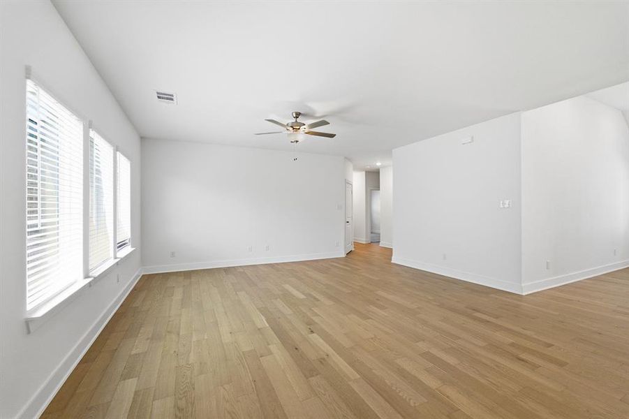 Spacious interior featuring wood-finish flooring, white walls, and bright window treatments
