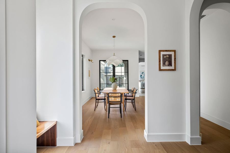 Elegant arched doorways frame a spacious dining area with pristine hardwood flooring and abundant natural light.