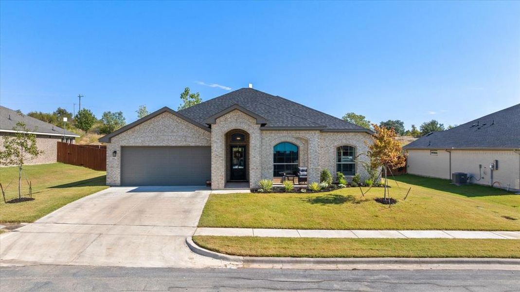 French country style house with brick siding, driveway, roof with shingles, and a garage