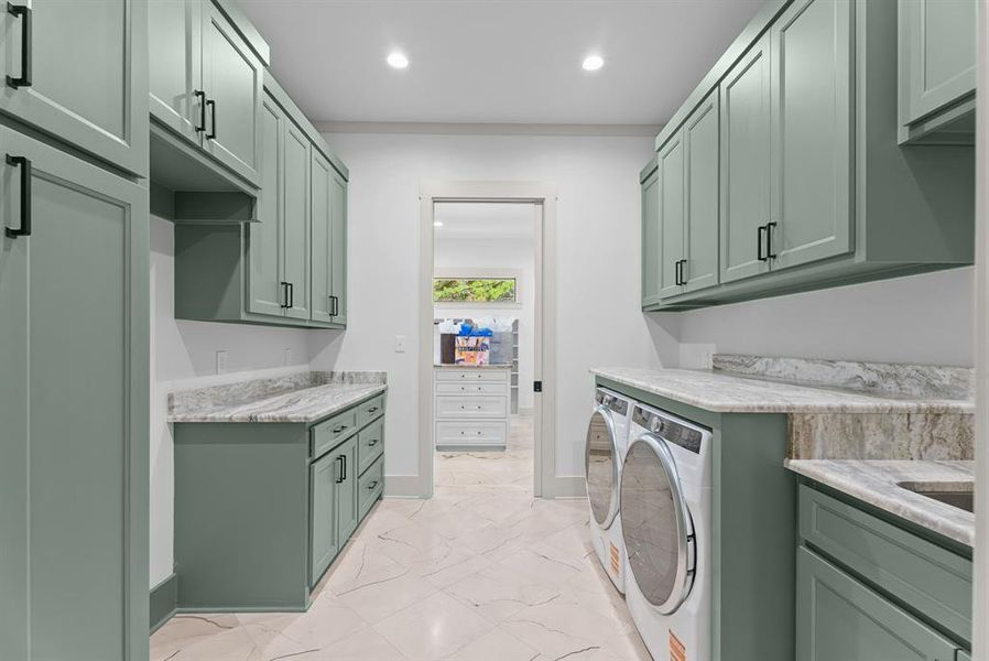 Laundry area featuring light marble finish floors, recessed lighting, independent washer and dryer, and cabinet space