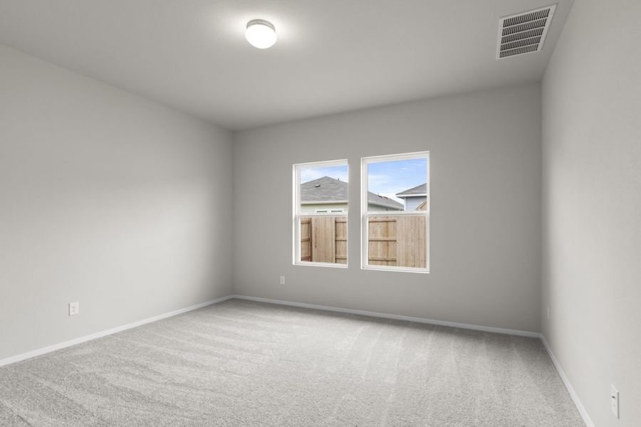 Image of a primary bathroom with beige walls, tan carpeting, two windows and white trim