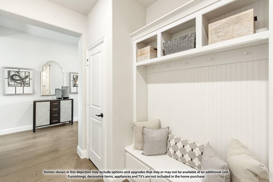 Mudroom with white built-in bench, coat hooks, and upper storage cubbies with baskets